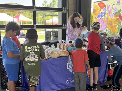 A group of six boys shop at a farmers market booth in Oak Park Michigan.